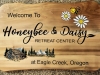 624  outdoor wooden sign for Honeybee & Daisy Oregon Retreat. Graphics for bee, daisies and rustic cabin in mountain scene